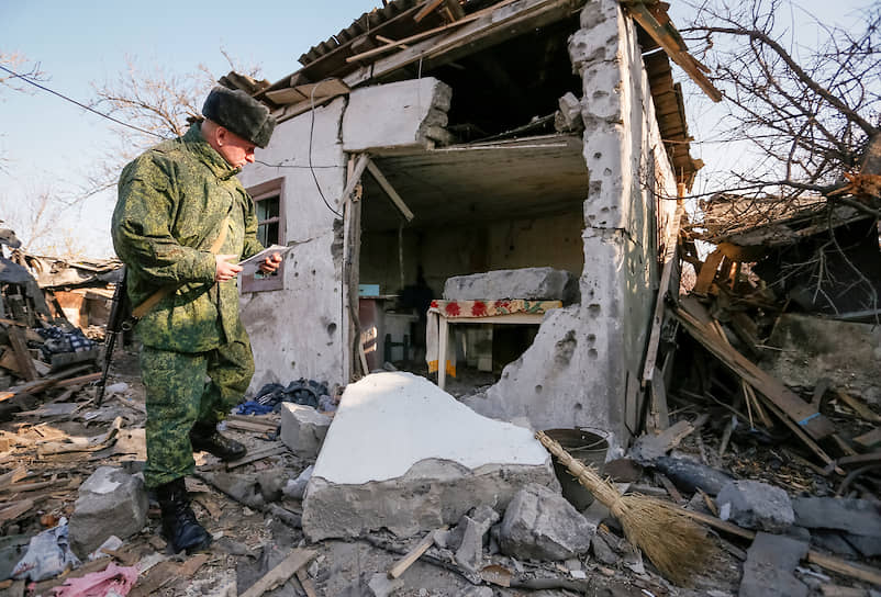 Донецк, Украина. Представитель вооруженных формирований самопровозглашенной ДНР осматривает разрушенный дом