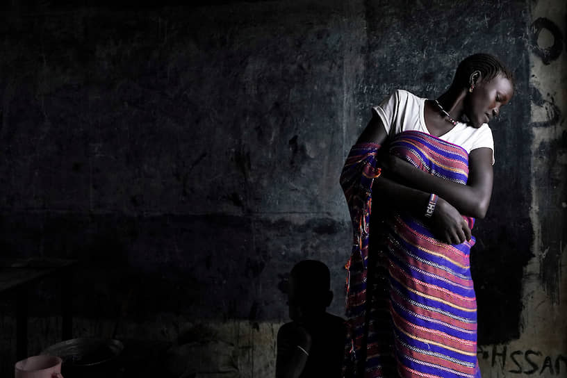 Пибор, Южный Судан. Женщина смотрит на прячущегося за ее платьем ребенка после того, как они и сотни тысяч других людей после сильных дождей и наводнений были вынуждены покинуть свои дома 