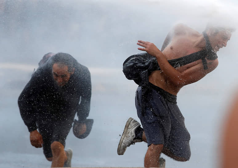 Сантьяго, Чили. Участники акции протеста убегают от водометов