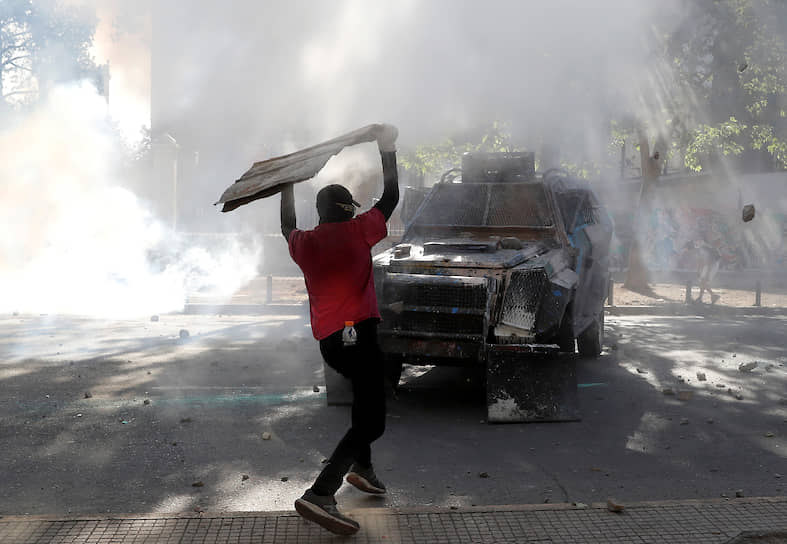 Сантьяго, Чили. Протестующий атакует полицейскую машину во время антиправительственной акции
