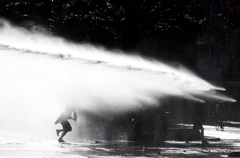 Сантьяго, Чили. Демонстрант убегает от водомета во время акций протеста