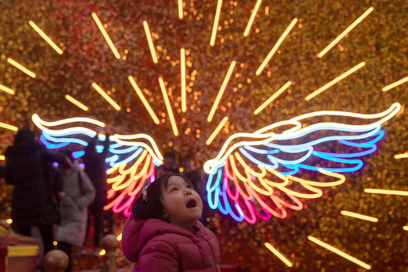 Пекин, Китай. Ребенок на фоне неоновых огней в канун Рождества 