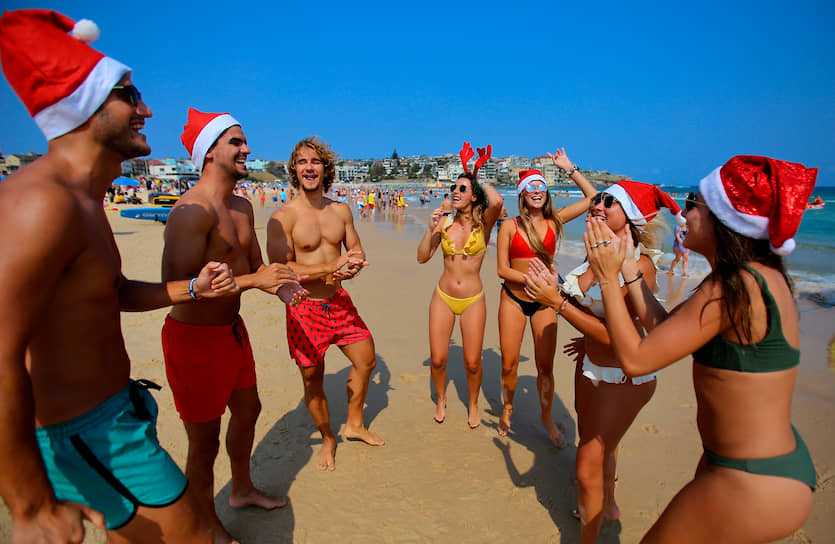Сидней, Австралия. Туристы в рождественских колпаках танцуют на пляже Бонди 