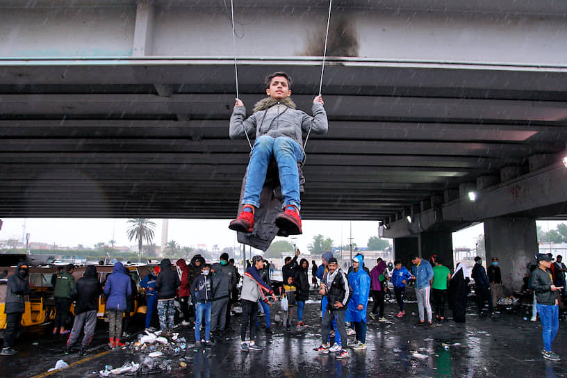Багдад, Ирак. Демонстрант качается на кабеле во время акций протеста