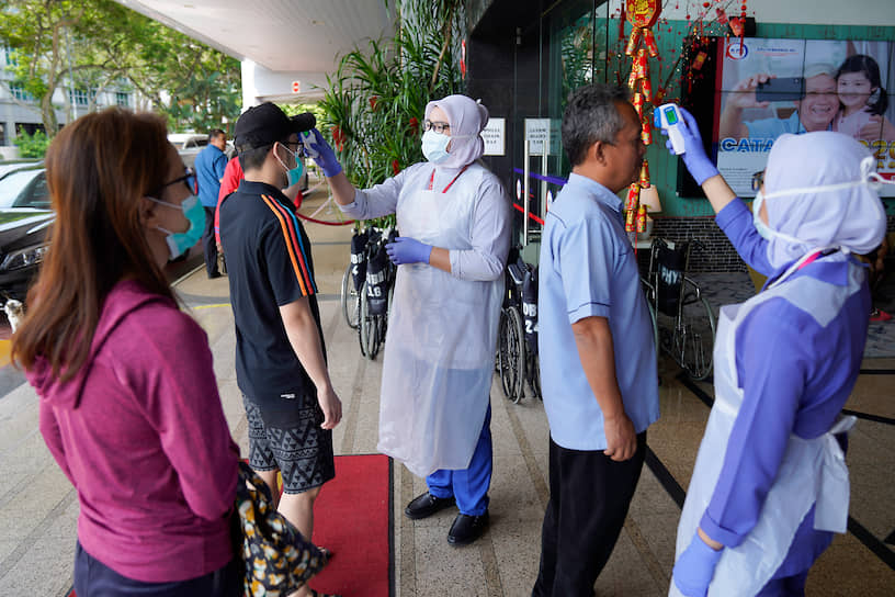 Медсестры проверяют температуру у посетителей больницы в Куала-Лумпуре, Малайзия