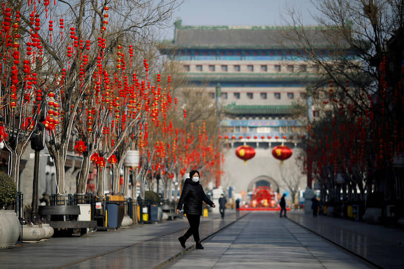 Пекин, Китай. Женщина идет по пешеходной улице в медицинской маске