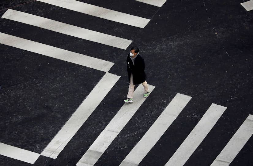 Сеул, Южная Корея. Мужчина в медицинской маске переходит дорогу