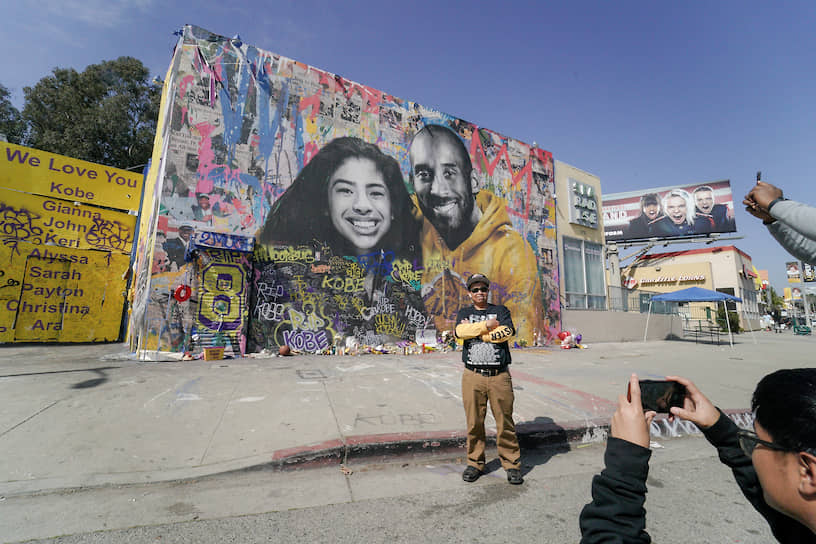 Фанаты фотографируются напротив стены, посвященной баскетболисту и его дочери