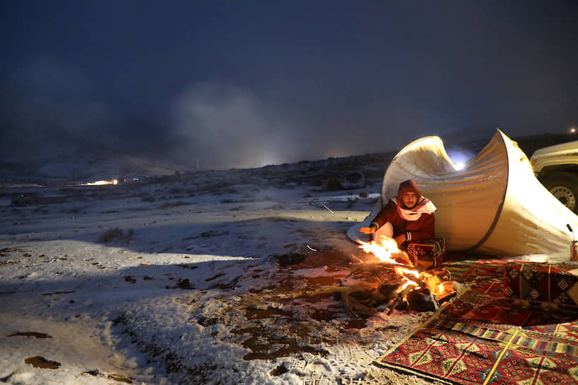Табук, Саудовская Аравия. Мужчина сидит возле палатки после снегопада