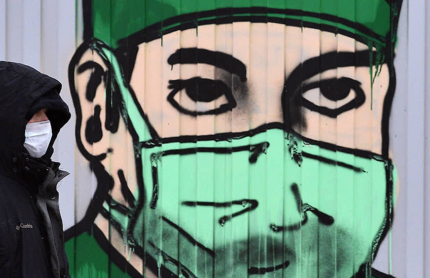 Москва. Мужчина в медицинской маске на фоне граффити с изображением врача