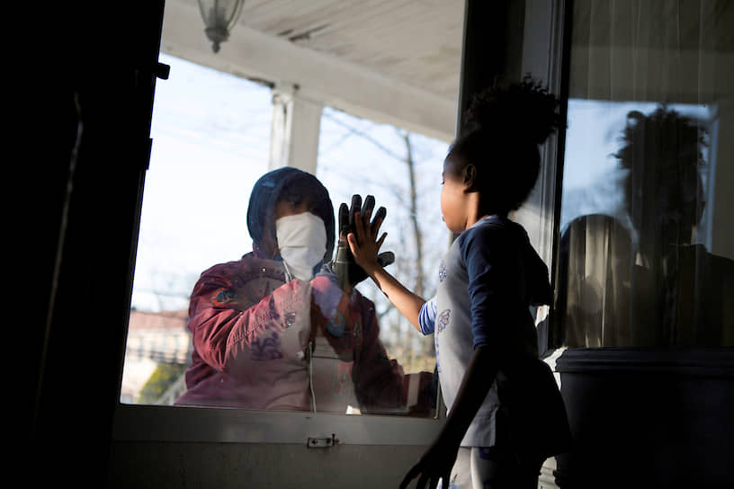 Нью-Рошелл, штат Нью-Йорк, США. Медицинский работник здоровается с дочерью через стекло, чтобы не заразить ее коронавирусом