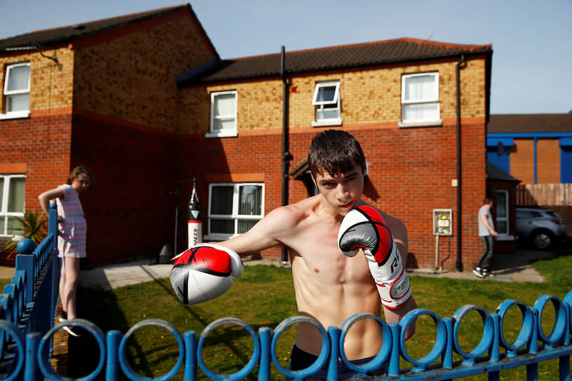 Белфаст, Великобритания. Молодой человек позирует в боксерских перчатках у себя во дворе