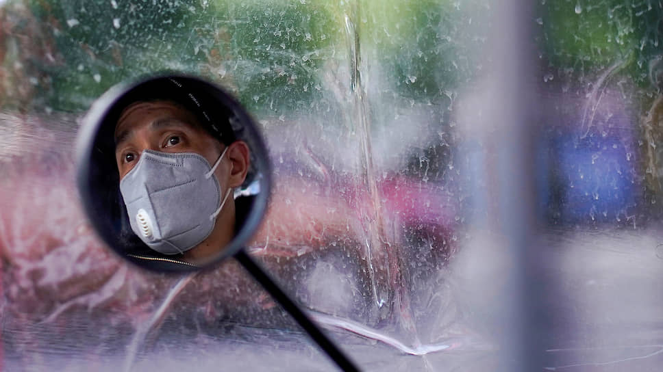 Ухань, Китай. Отражение лица водителя в зеркале заднего вида его мопеда 