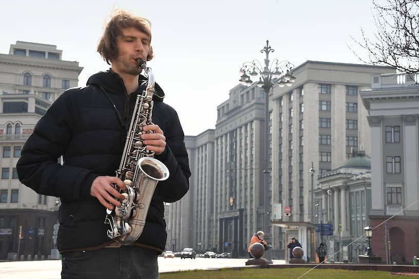 Москва. Уличный музыкант играет на саксофоне на фоне здания Госдумы
