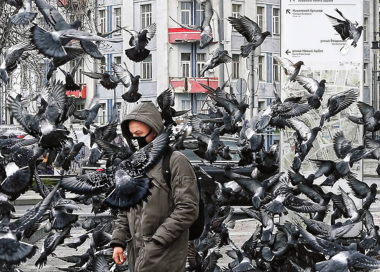 Москва. Мужчина в маске и голуби на площади Арбатские Ворота