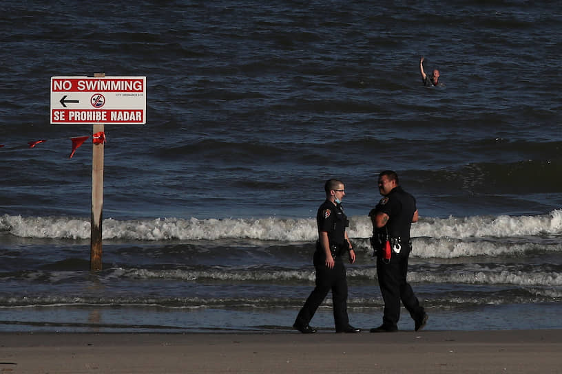 Галвестон, штат Техас, США. Мужчина машет полицейским на пляже