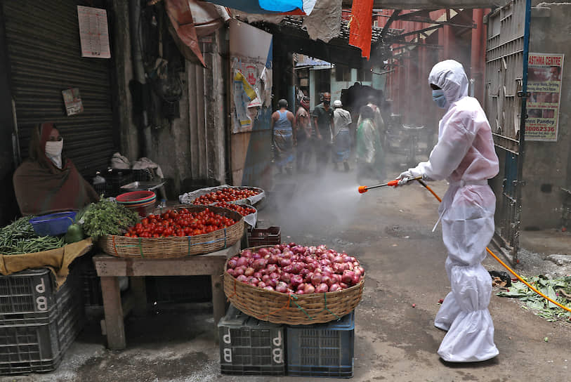Муниципальный работник проводит дезинфекцию рынка в Калькутте