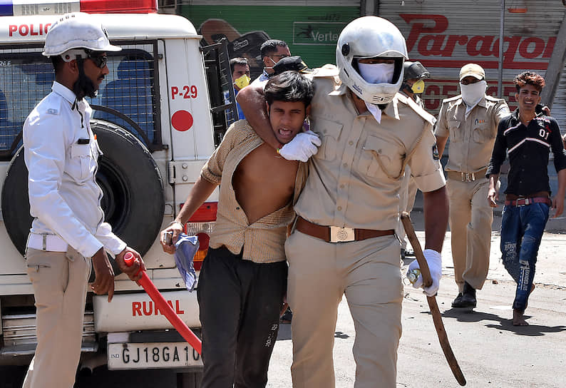 Полицейские задерживают протестующих в Сурате, которые требовали права вернуться в свои родные штаты