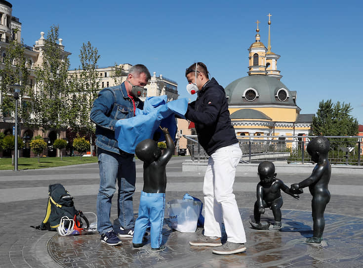 Украинский скульптор Владимир Журавель с ассистентом надевают символические защитные костюмы на скульптуры в рамках акции поддержки медработников