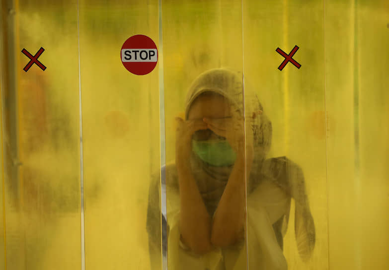 Джакарта, Индонезия. Женщину опрыскивают дезинфицирующим средством перед входом в торговый центр