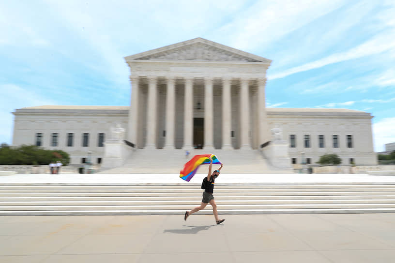 Вашингтон, США. Мужчина бежит с радужным флагом перед зданием Верховного суда, подтвердившего запрет на дискриминацию секс-меньшинств на работе 