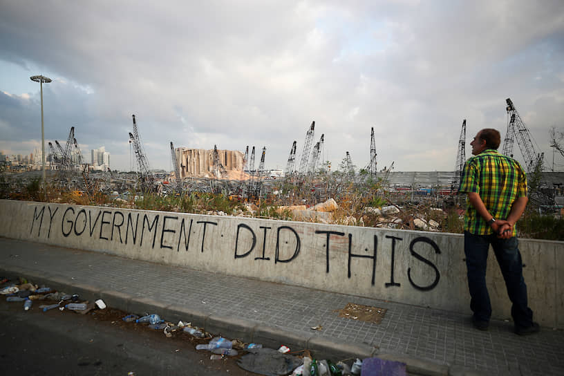 Бейрут, Ливан. Мужчина стоит рядом с граффити «мое правительство сделало это» около разрушенного взрывом порта