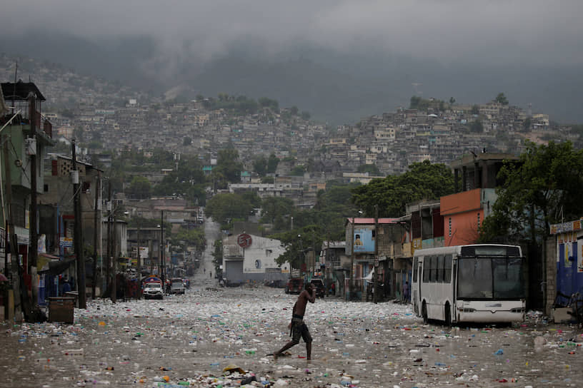 Порт-о-Пренс, Гаити. Местный житель переходит подтопленную улицу 