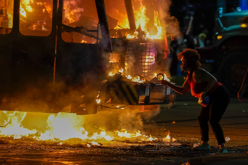 Кеноша, США. Протестующая подкуривает от мусоровоза, подожженного во время протестов в штате Висконсин