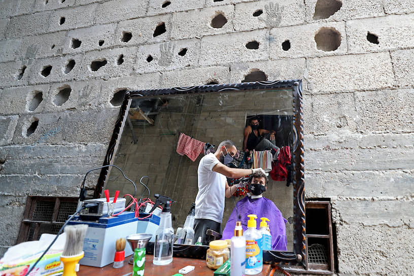 Газа, Палестина. Парикмахер подстригает волосы клиенту 