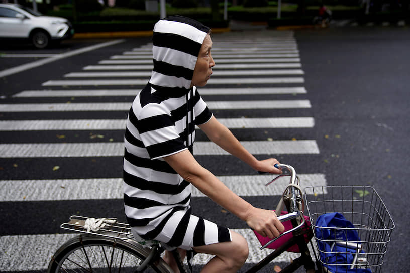 Шанхай, Китай. Женщина на велосипеде на пешеходном переходе