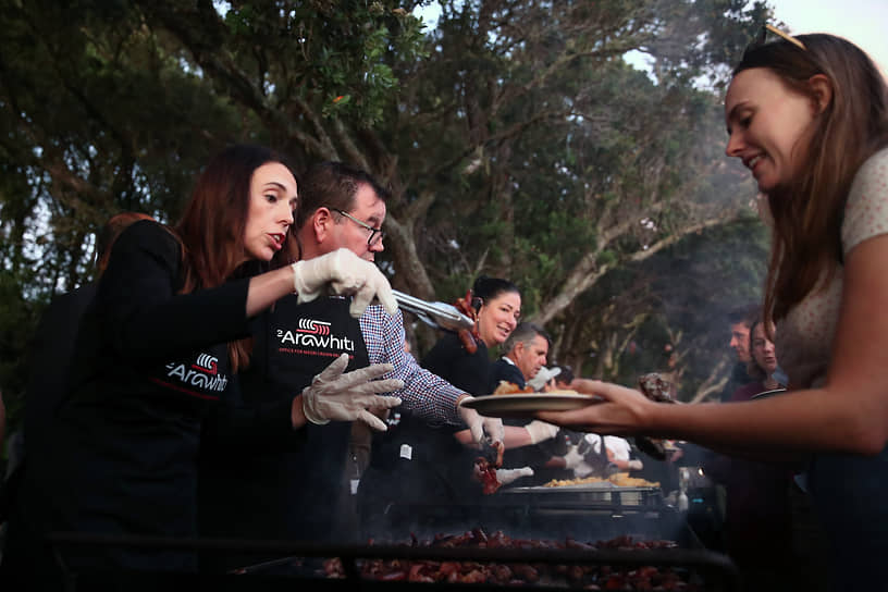 Глава новозеландского правительства Джасинда Ардерн (слева) и министр финансов Грант Робертсон (второй слева) готовят мясо на барбекю во время национального праздника День Вайтанги, февраль 2021 года