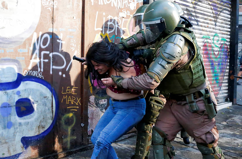 Вальпараисо, Чили. Полицейский задерживает участницу антиправительственной акции протеста 