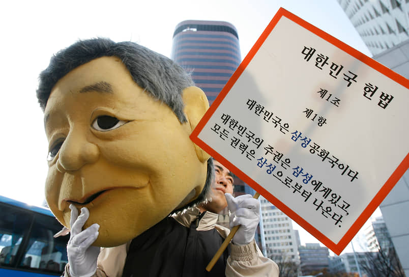 Протестующий из Корейской конфедерации профсоюзов держит куклу, напоминающую председателя Samsung Group Ли Кун Хи, и табличку с критикой Samsung на митинге перед штаб-квартирой компании в Сеуле 16 ноября 2007 года