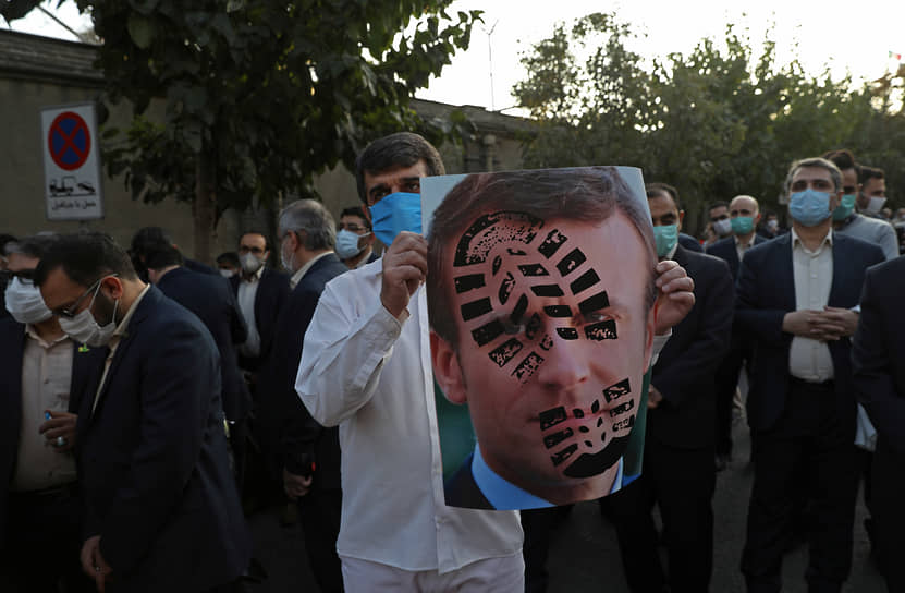Участник митинга в Тегеране с портретом Эмманюэля Макрона и отпечатком ботинка на нем