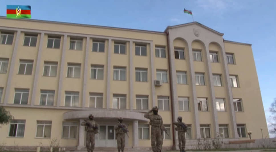Кадр из опубликованного Министерством обороны Азербайджана видео: азербайджанские военнослужащие отдают честь перед зданием мэрии Шуши, на крыше которой развевается национальный флаг