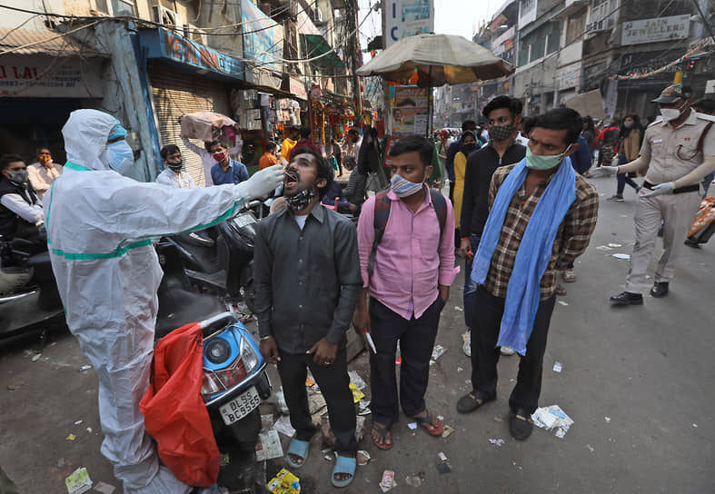 Дели, Индия. Медработник на рынке берет мазок на коронавирус