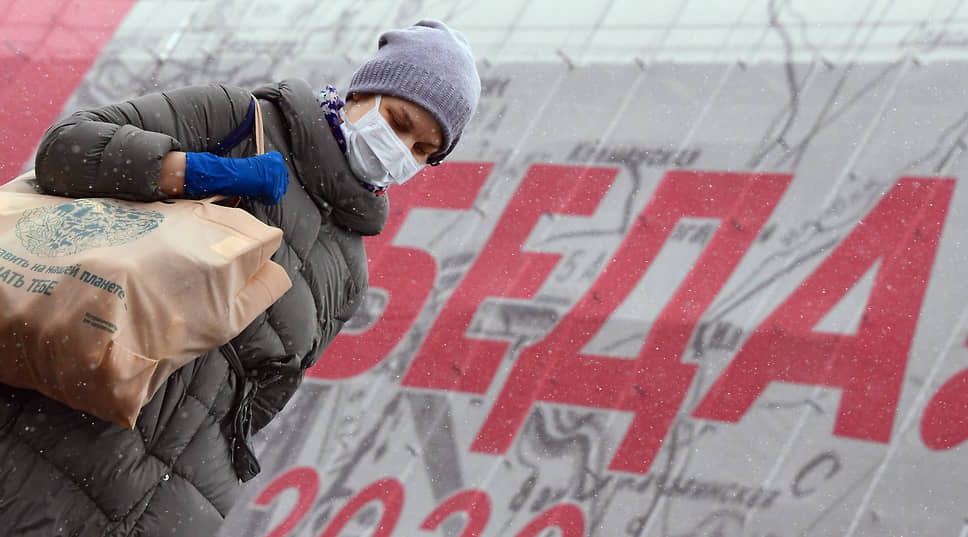 Девушка в медицинской маске идет по улице в Москве