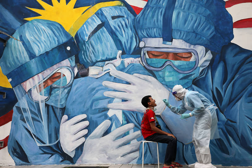 Шах-Алам, Малайзия. Медработник берет мазок для теста на коронавирус 