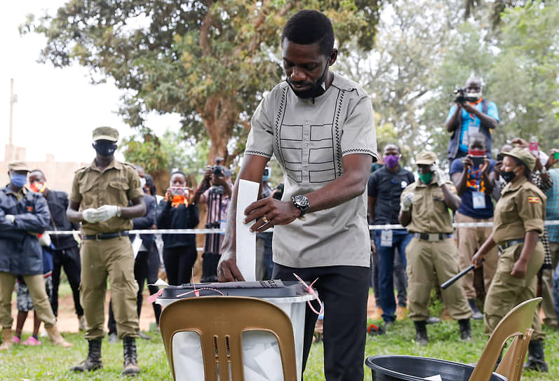 Кандидат в президенты Уганды Боби Вайн опускает в урну избирательный бюллетень