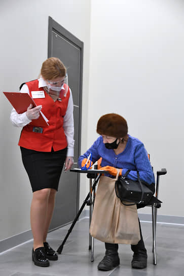 Москва, Россия. Сотрудница МФЦ помогает посетительнице заполнить анкету на вакцинацию от коронавируса