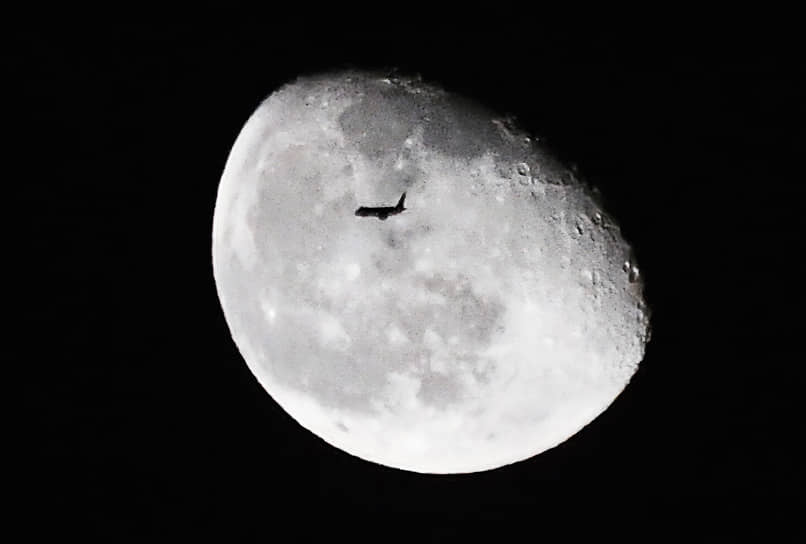Летящий самолет на фоне Луны 
