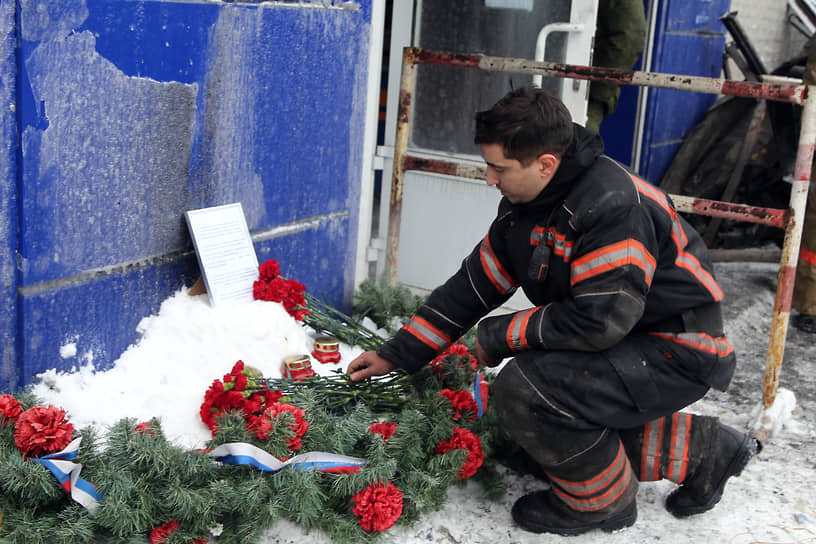 Сотрудник МЧС возлагает цветы к стенам склада, где погиб его коллега