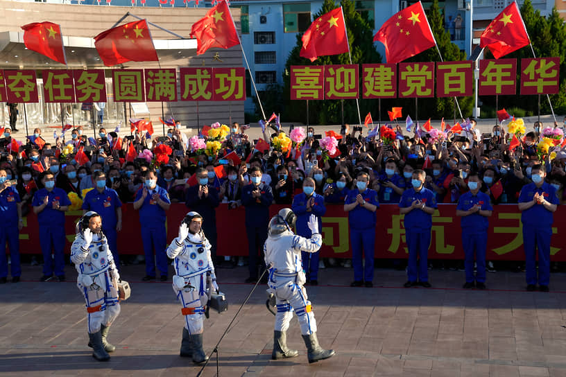 Тан Хунбо, Лю Бомин и Не Хайшэн (слева направо) машут собравшимся перед тем, как сесть в космический корабль