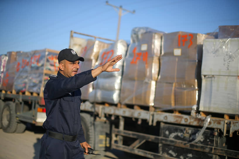Полицейский из Палестины регулирует движение грузовиков, везущих одежду на экспорт из сектора Газа