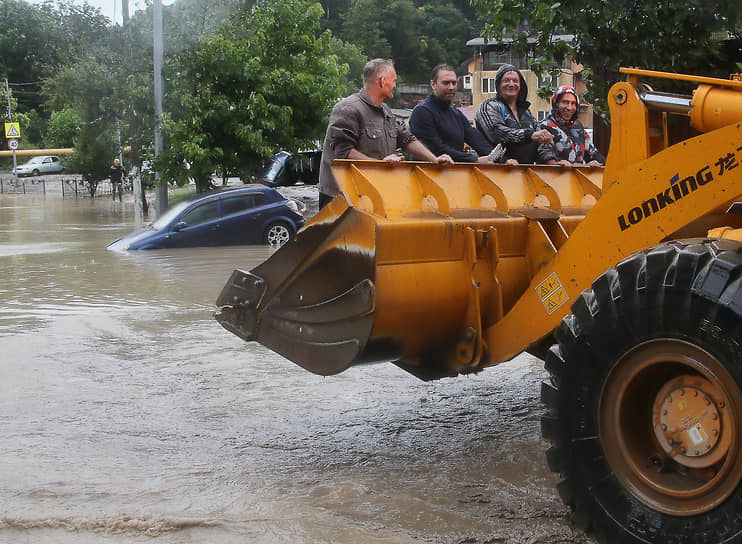 Во время сильных дождей в море попало большое количество мусора&lt;br>
На фото: рабочие возле автомобиля на затопленной улице в микрорайоне Кудепста