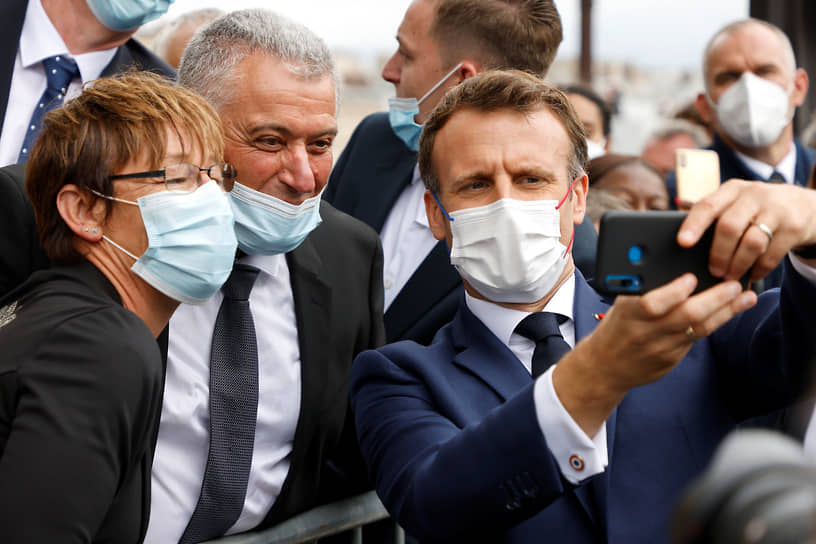 Президент Франции Эмманюэль Макрон (справа) делает селфи со зрителями, пришедшими на парад