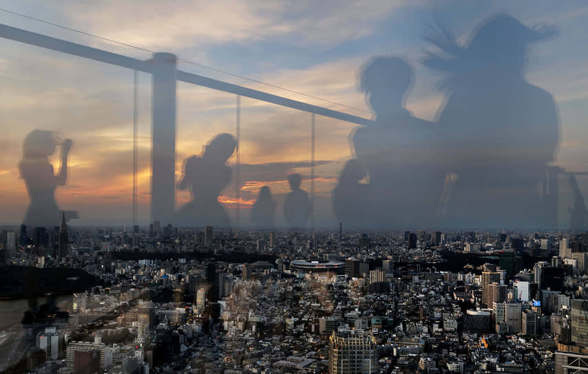 Токио, Япония. Люди отражаются в стекле на смотровой площадке 