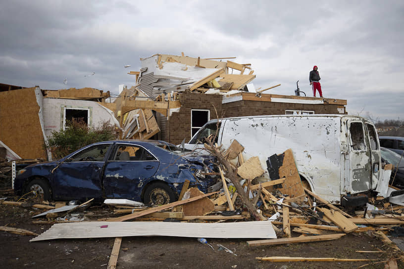 Житель города Боулинг-Грин (Кентукки) стоит на крыше своего дома, разрушенного торнадо
