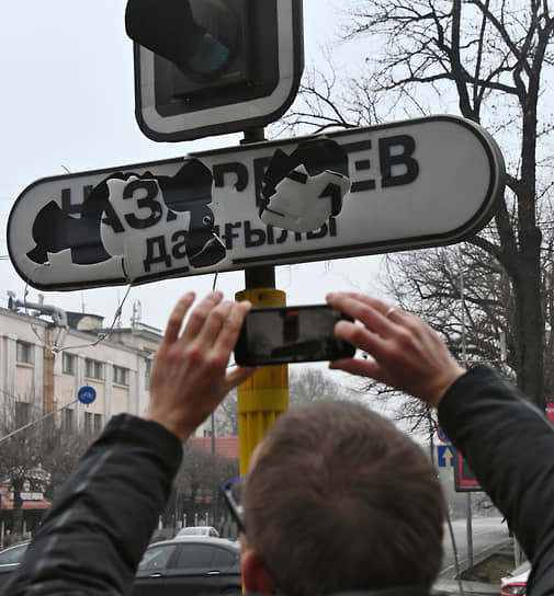 Мужчина фотографирует разбитый уличный указатель «проспект Назарбаева»