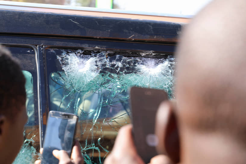 Люди фотографируют стекло президентского автомобиля, по которому велась стрельба